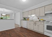 Thumbnail 3 of 47 - A kitchen with white appliances and wooden floors.