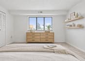 Thumbnail 21 of 31 - A bedroom with a large bed, a window with blinds, and a wooden dresser.
