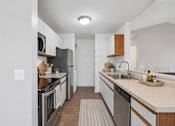 Thumbnail 7 of 26 - A modern kitchen with a refrigerator, oven, and sink.