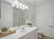 Thumbnail 11 of 26 - A bathroom with a white countertop and a white toilet.