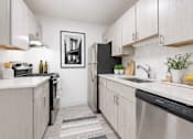 Thumbnail 1 of 29 - A kitchen with white cabinets and a black fridge.