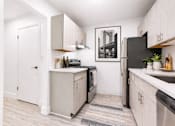 Thumbnail 2 of 29 - A kitchen with a black refrigerator and a black and white framed picture on the wall.
