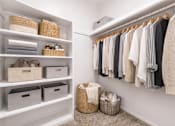 Thumbnail 8 of 29 - A white closet with clothes hanging and baskets on the shelves.