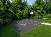 Thumbnail 28 of 35 - A basketball court surrounded by trees and a bench.