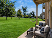 Thumbnail 22 of 35 - A patio with a chair and table overlooking a grassy field.