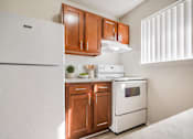 Thumbnail 17 of 35 - A white refrigerator is in a kitchen with wooden cabinets.