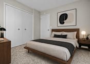 Thumbnail 12 of 35 - A bedroom with a large bed, a wooden nightstand, and a framed picture on the wall.