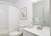 Thumbnail 21 of 35 - A white bathroom with a toilet, sink, and shower.