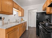 Thumbnail 1 of 23 - A kitchen with wooden cabinets and a black stove.