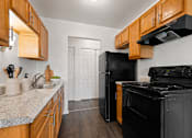 Thumbnail 2 of 23 - A kitchen with black appliances and wooden cabinets.