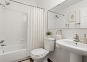 Thumbnail 12 of 23 - A white bathroom with a toilet, sink, and bathtub.