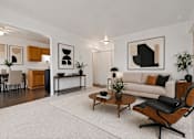 Thumbnail 5 of 23 - A modern living room with a white couch, a coffee table, and a chair.