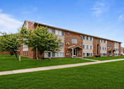 Thumbnail 19 of 23 - A large brick building with a green lawn in front.