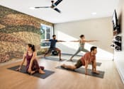 Thumbnail 49 of 58 - Three people doing yoga in a room with a wallpapered wall.