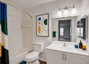 Thumbnail 18 of 39 - A bathroom with a white toilet, a white sink, and a mirror.