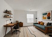 Thumbnail 22 of 39 - A room with a desk, a couch, and a painting on the wall.