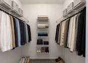 Thumbnail 20 of 39 - A walk in closet with clothes and shoes.
