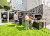 Thumbnail 36 of 58 - Three people are standing outside a house with a grill.