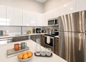 Thumbnail 19 of 58 - A modern kitchen with a stainless steel refrigerator and white cabinets.
