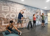 Thumbnail 48 of 58 - A group of people exercising in a gym with a brick wall that says "BREAK YOUR".