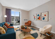 Thumbnail 11 of 58 - A living room with a blue couch, a wooden coffee table, and a large window with a view of the city.