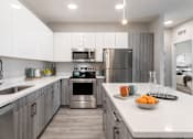 Thumbnail 12 of 64 - A modern kitchen with stainless steel appliances and white countertops.