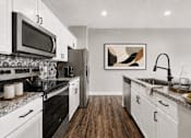Thumbnail 9 of 39 - A modern kitchen with white cabinets and a black stove top.