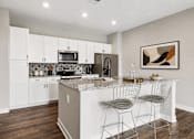 Thumbnail 8 of 39 - A kitchen with white cabinets and a granite countertop.