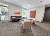 Thumbnail 50 of 64 - A living room with a grey sofa, a wooden table and chairs, and two pieces of artwork on the wall.