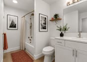 Thumbnail 9 of 87 - A white bathroom with a toilet, sink, and pictures on the wall.