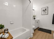 Thumbnail 11 of 87 - A white bathroom with a black towel hanging on the door.