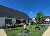 Thumbnail 36 of 39 - A group of people practicing yoga on mats outside a building.
