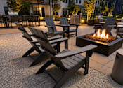 Thumbnail 31 of 39 - A fire pit is surrounded by chairs on a patio.