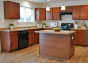 Thumbnail 3 of 20 - A kitchen with wooden cabinets and a black refrigerator.