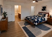 Thumbnail 6 of 20 - A bedroom with a bed, a ceiling fan, and a rug.