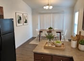 Thumbnail 14 of 20 - A kitchen with a black refrigerator and a dining table with chairs.