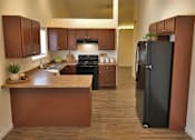 Thumbnail 13 of 20 - A kitchen with a black refrigerator and brown cabinets.