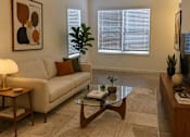 Thumbnail 15 of 20 - A living room with a beige couch, a coffee table, and a ceiling fan.