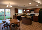 Thumbnail 2 of 20 - A kitchen with wooden floors and brown cabinets.