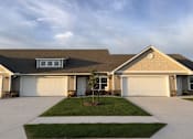 Thumbnail 1 of 20 - A house with a brown roof and two white garage doors.