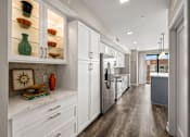 Thumbnail 15 of 58 - A kitchen with white cabinets and a wooden floor.