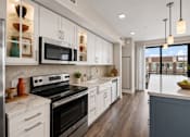 Thumbnail 16 of 58 - A modern kitchen with white cabinets and a black stove top oven.