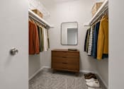 Thumbnail 64 of 87 - Walk-in closet with hanging rods and dresser at Village Club of Farmington Hills Apartments, Farmington Hills, MI 48331