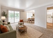 Thumbnail 14 of 26 - A living room with a green couch, a coffee table, and a rug.