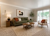 Thumbnail 15 of 26 - A living room with a green couch, a coffee table, and a painting on the wall.