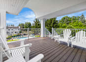 Thumbnail 69 of 87 - Covered balcony with white chairs and railing at Village Club of Farmington Hills Apartments, Farmington Hills, Michigan