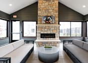 Thumbnail 39 of 39 - A modern living room with a stone fireplace and a painting above it.