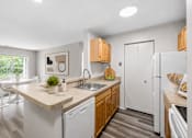 Thumbnail 32 of 87 - Galley kitchen with breakfast bar and modern finishes at Village Club of Farmington Hills Apartments, Farmington Hills, MI