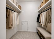 Thumbnail 39 of 87 - Walk-in closet with bench seating and wicker storage baskets at Village Club of Farmington Hills Apartments, Farmington Hills, 48331