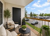 Thumbnail 40 of 87 - Covered balcony with seating and parking lot views at Village Club of Farmington Hills Apartments, Farmington Hills, Michigan